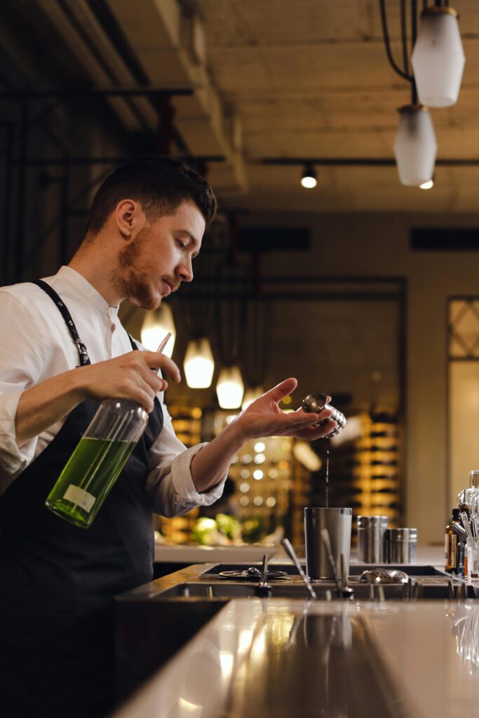 Professional bartender pouring a cocktail with precision in a stylish bar setting.